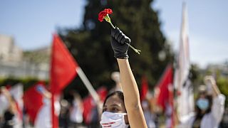 A protester from the communist party-affiliated PAME union wearing a mask to protect against coronavirus, holds a carnation during a May Day rally outside the Greek Parliament