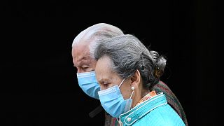An elderly couple wearing face masks walks in Madrid on April 30, 2020 during a national lockdown to prevent the spread of the COVID-19 disease