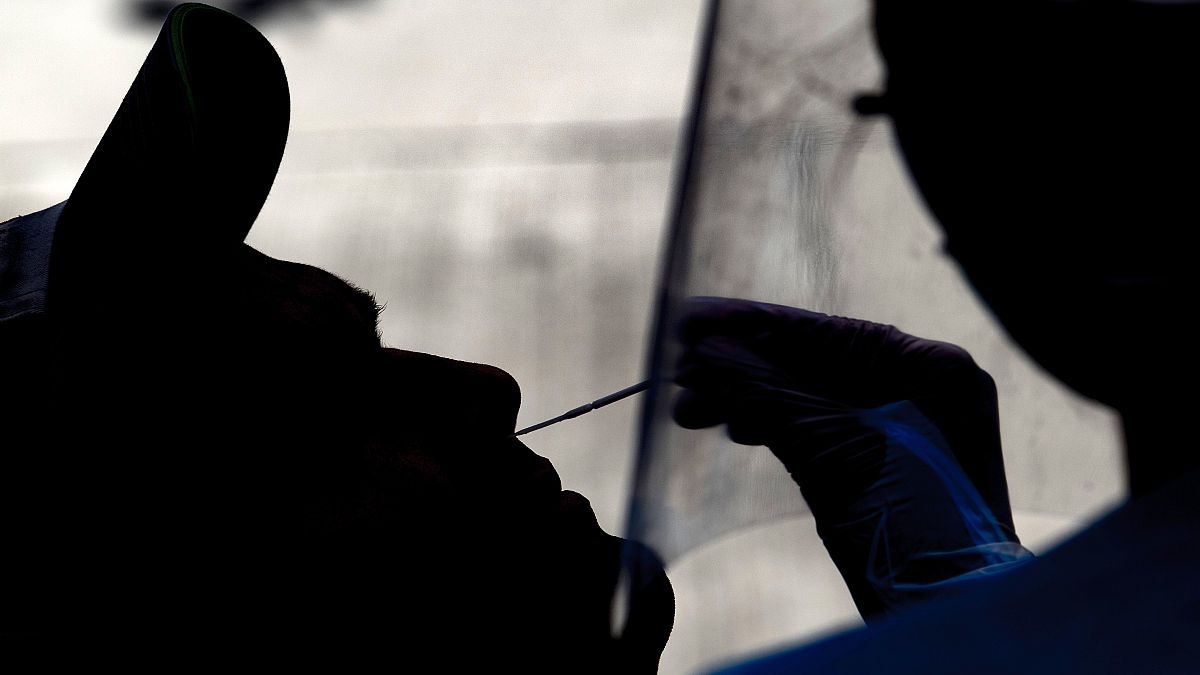A health worker collects a nasal swab sample from a man on a car to be tested for COVID-19  at a gas station in Santiago on April 30, 2020. (Photo by MARTIN BERNETTI / AFP)