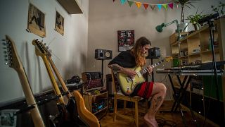 A koronavírus-járvány miatt önkéntes karanténban lévő zenész gitárján játszik budapesti otthonában 2020. április 6-án.