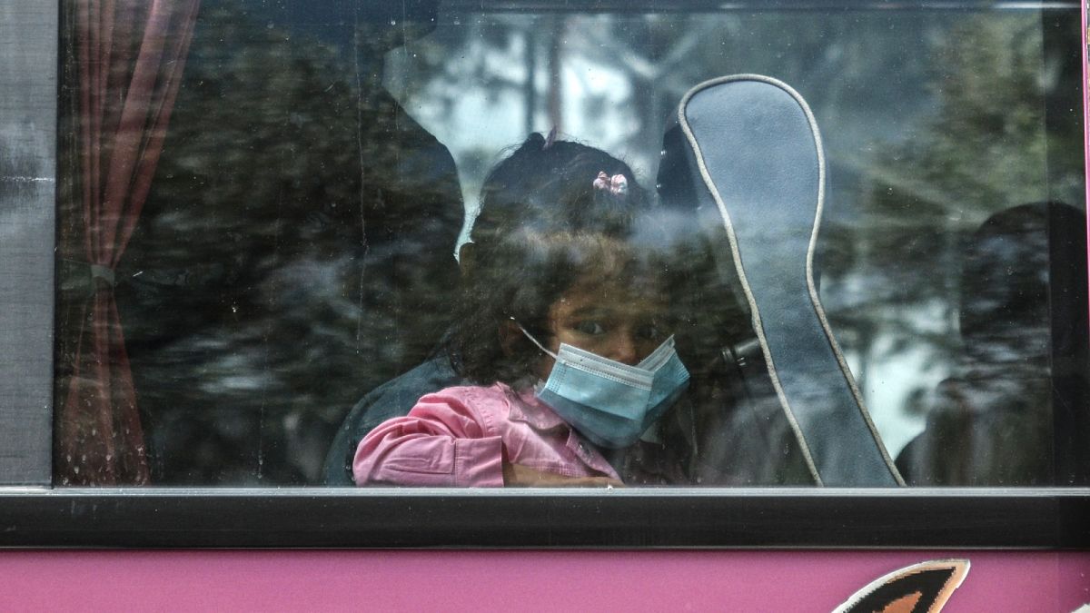 A child migrant looks from a bus window outside Moria camp on her way to the port of Mytilene, on the northeastern Aegean island of Lesbos, Greece, on May 3, 2020