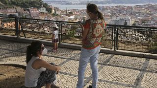 Les gens profitent du beau temps depuis un point de vue qui surplombe la vieille ville de Lisbonne le dimanche 3 mai 2020.