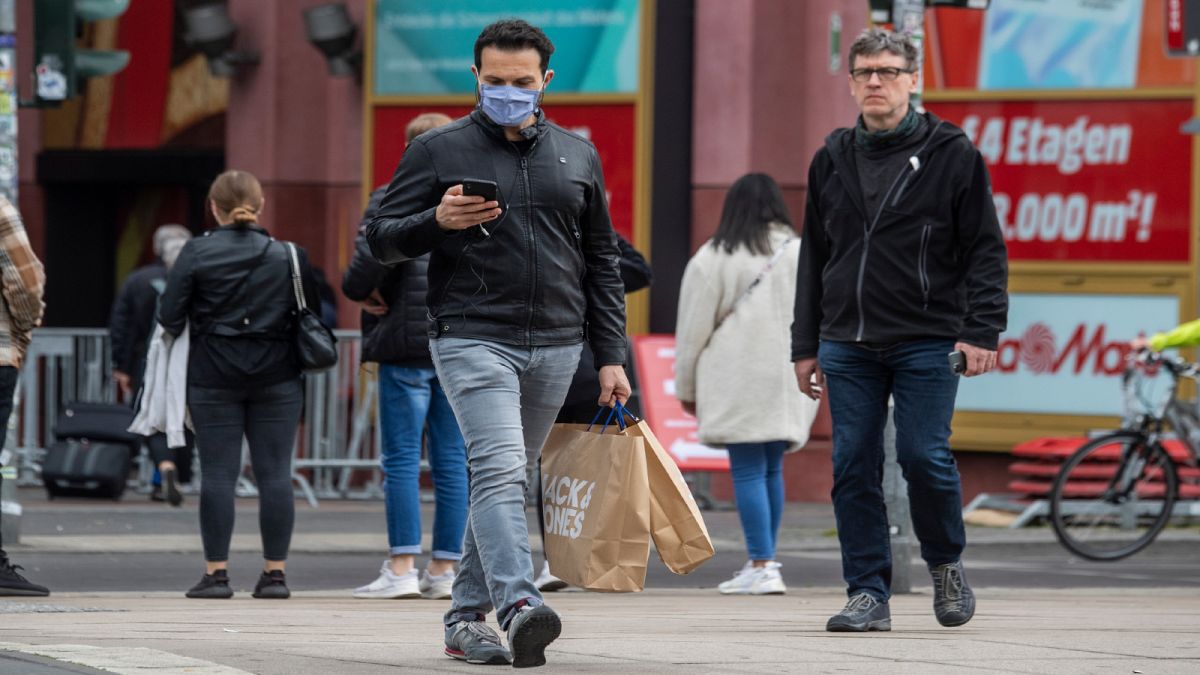 رجل يرتدي قناع وجه يخرج من مركز تسوق في برلين في 29 أبريل 2020 وسط انتشار فيروس كورونا