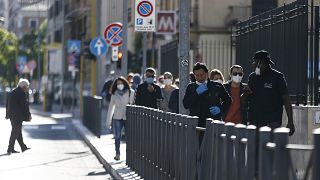 People crowd a street in Rome, Monday, May 4, 2020. Italy began stirring again Monday after a two-month coronavirus shutdown