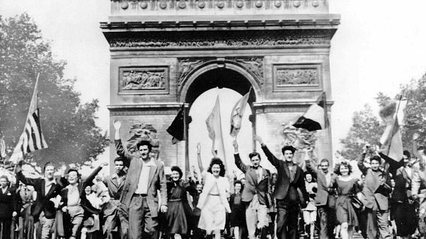 Parisians march through the Arc de Triomphe jubilantly waving flags of the Allied Nations as they celebrate the end of World War II on May 8, 1945. Parisians march through the Arc de Triomphe jubilantly waving flags of the Allied Nations as they celebrate the end of World War II on May 8, 1945.