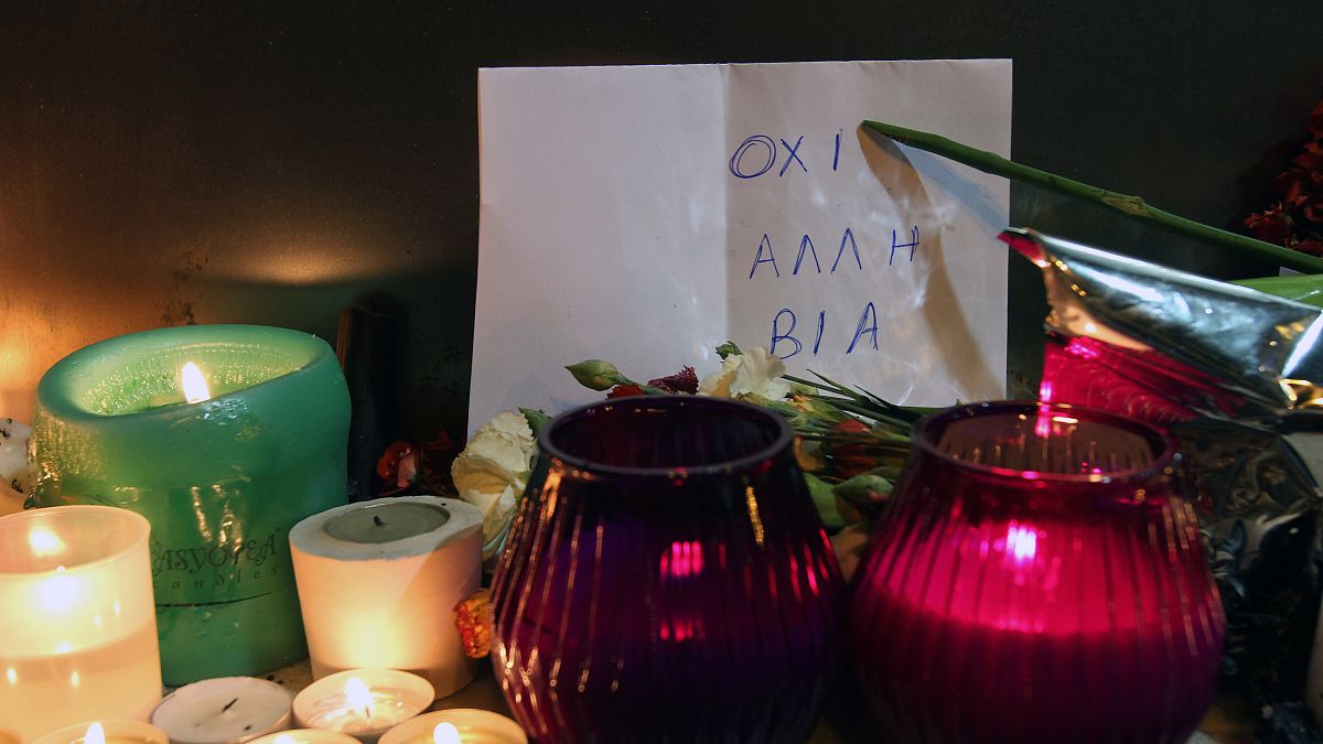 The sign behind the candles reads ''No more violence'' at the Marfin Egnatia Bank where three employees burnt to death in 2010