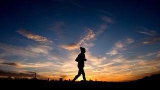A jogger is silhouetted against the morning sky during sunrise in Hannover, northern Germany, Jan. 3, 2014. (AP Photo/dpa, Julian Stratenschulte)