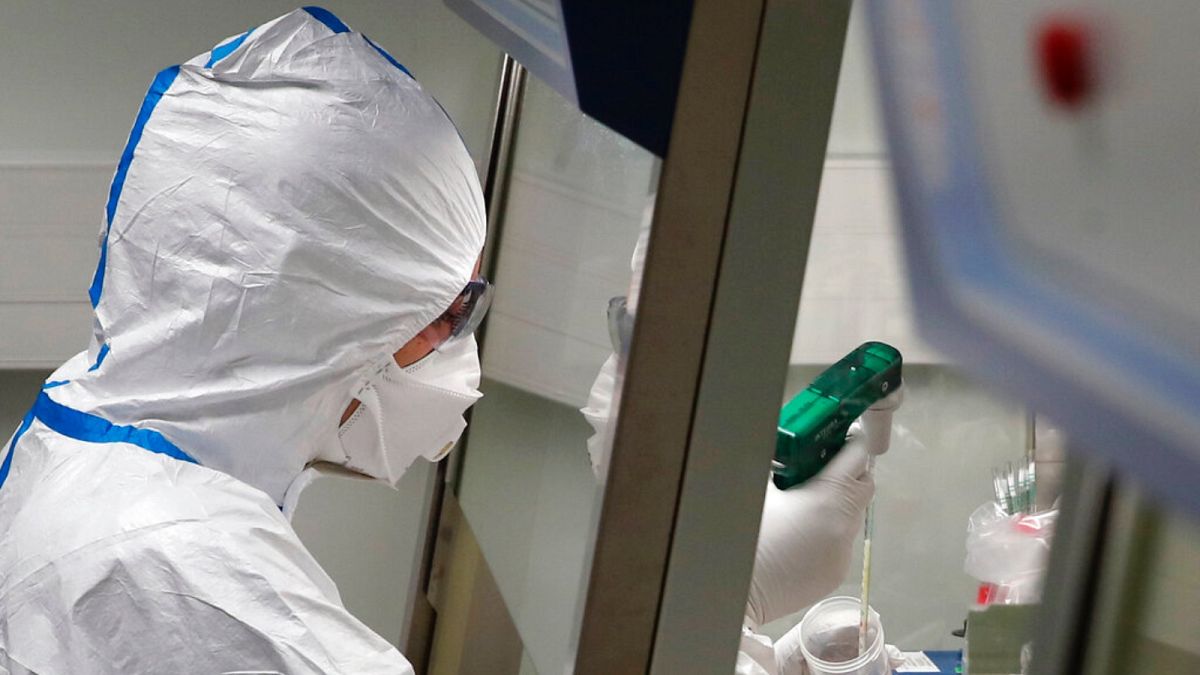 French lab scientist in hazmat gear inserting liquid in test tube manipulates potentially infected patient samples at Pasteur Institute in Paris, Thursday, Feb. 6, 2020. 