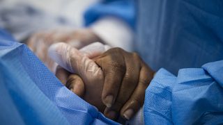 A nurse practitioner talks to a patient and holds her hand while a doctor administers an IV at Roseland Community Hospital in Chicago.