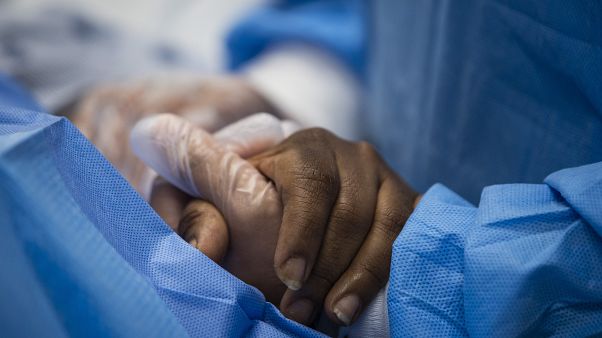 A nurse practitioner talks to a patient and holds her hand while a doctor administers an IV at Roseland Community Hospital in Chicago.