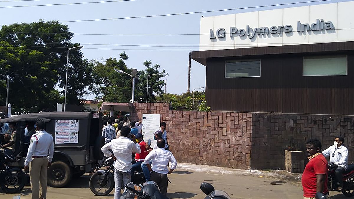 Policemen stand guard as people gather in front of an LG Polymers plant following a gas leak incident in Visakhapatnam on May 7, 2020