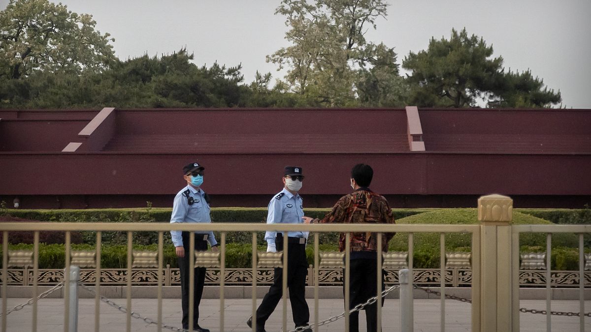 شرطيان صينيان يتحدثان إلى شخص قرب ساحة تياننمان في بيكين.