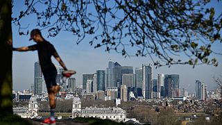 London's financial district Canary Wharf is seen as a man exercises in Greenwich Park