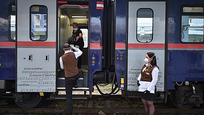 A woman is helped by conductor while boarding a train in Timisoara