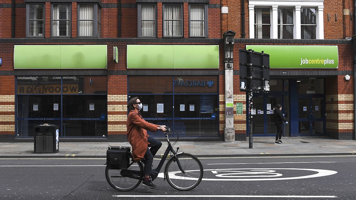 File photo: In this Thursday, April 30, 2020 photo, a woman wearing a mask to protect against coronavirus, rides a bicycle past a job centre in Shepherd's Bush, London.