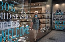 A woman wearing a mask to prevent the spread of the coronavirus exits a shoe store in central Athens, Monday, May 11, 2020, following the reopening of retail shops. 