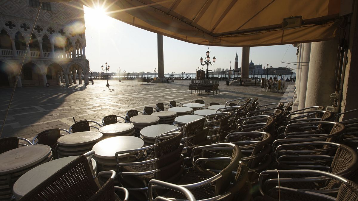 In this Monday, April 6, 2020 file photo, chairs and tables are piled in front of a bar in St. Mark's Square, in Venice during a lockdown to prevent the spread of COVID-19