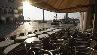 In this Monday, April 6, 2020 file photo, chairs and tables are piled in front of a bar in St. Mark's Square, in Venice during a lockdown to prevent the spread of COVID-19