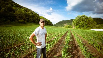 Man standing in a field staring directly at the camera.