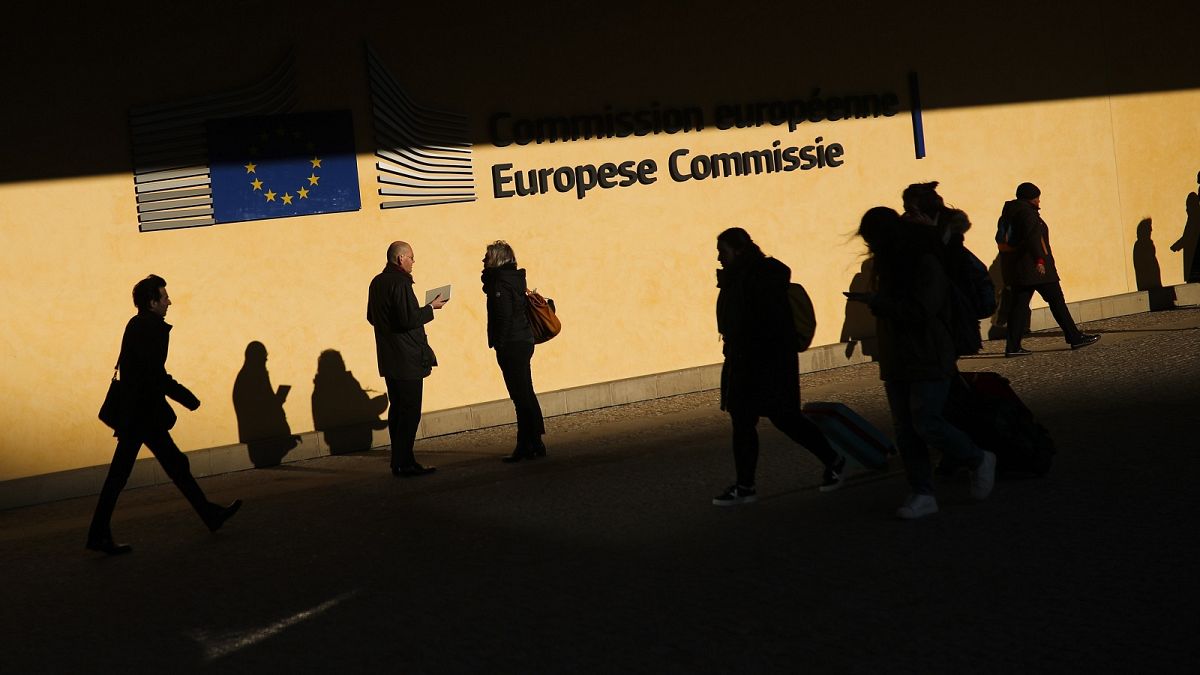 People walk past the European Commission headquarters in Brussels, Friday, Feb. 7, 2020