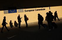 People walk past the European Commission headquarters in Brussels, Friday, Feb. 7, 2020