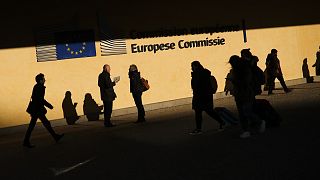 People walk past the European Commission headquarters in Brussels, Friday, Feb. 7, 2020