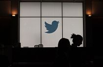 In this file photograph taken on August 14, 2019, employees walk past an illuminated Twitter logo as they leave the company's headquarters in San Francisco.