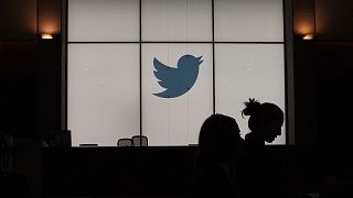 In this file photograph taken on August 14, 2019, employees walk past an illuminated Twitter logo as they leave the company's headquarters in San Francisco.