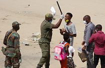 Um agente de autoridade interpela um jovem no distrito de Kifangondo, em Luanda