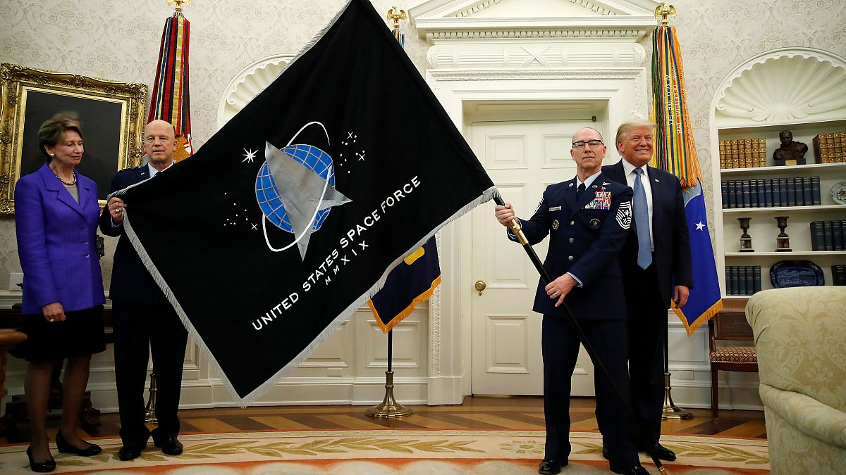 ضباط من وزارة الدفاع الأمريكية يعرضون علم قوة الفضاء الجديد على الرئيس الأمريكي في البيت الابيض