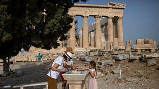 Visitors wash their hands in front of ancient Parthenon temple at the Acropolis hill of Athens, on Monday, May 18, 2020.