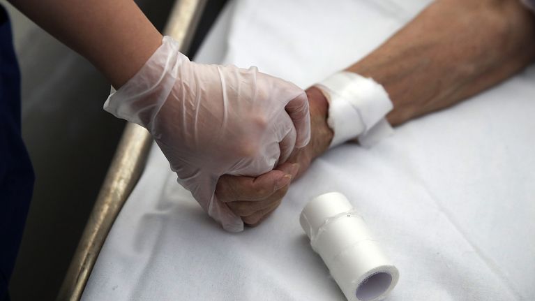 A medical worker holds the hand of a patient in Greece in 2020.