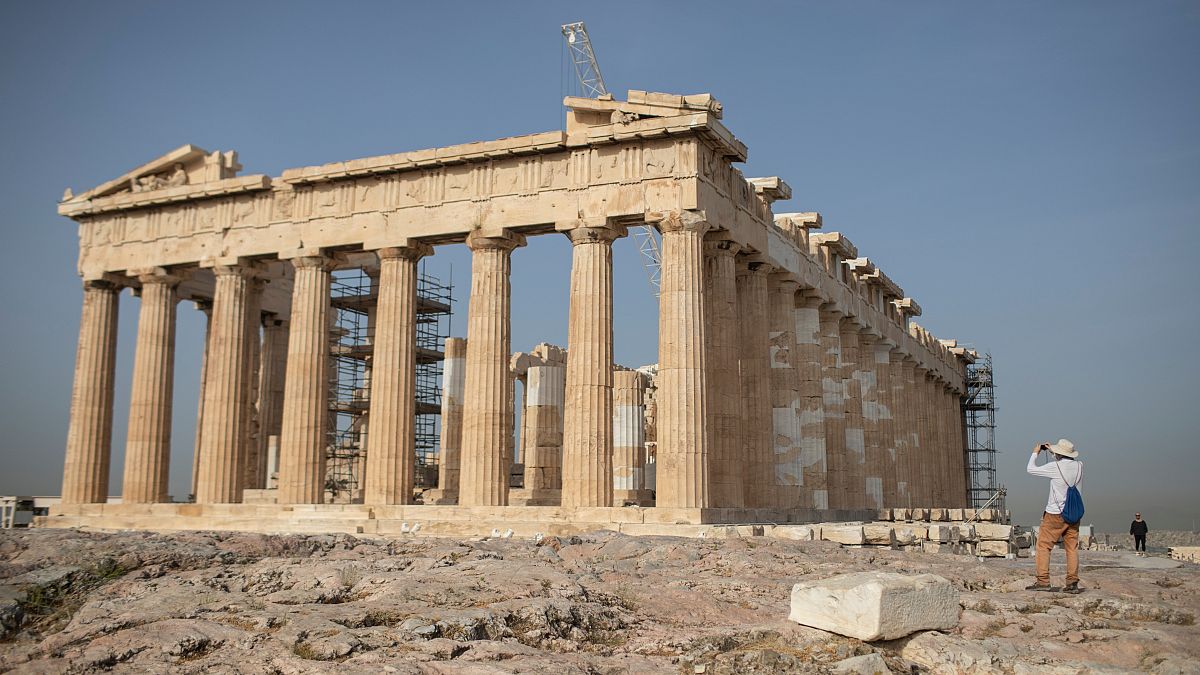 A man takes a picture next the ancient Parthenon temple at the Acropolis hill of Athens, on Monday, May 18, 2020