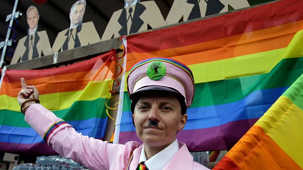 A participant gestures with a rainbow flag under the portraits of Hungarian politicans during the gay rights Pride Parade in Budapest (Photo by PETER KOHALMI / AFP) A participant gestures with a rainbow flag under the portraits of Hungarian politicans during the gay rights Pride Parade in Budapest (Photo by PETER KOHALMI / AFP)
