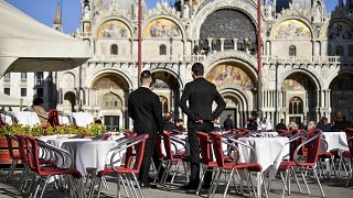 Dos camareros esperan a los clientes en un restaurante de la Plaza de San Marcos el 28 de febrero de 2020 en Venecia, Italia.