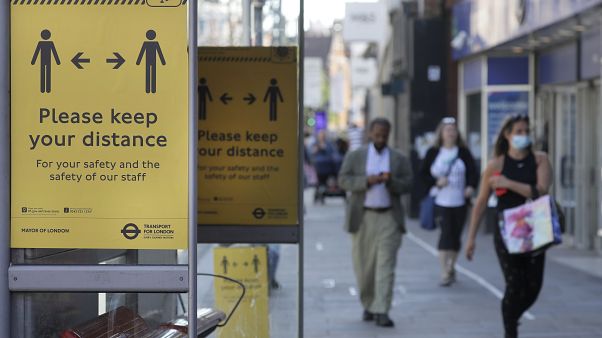 Signs advise people to social distance on a bus stop along a high street, in London Signs advise people to social distance on a bus stop along a high street, in London