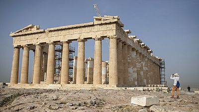 A man takes a picture next the ancient Parthenon temple at the Acropolis hill of Athens.