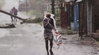 A man covers himself with a plastic sheet and walks in the rain ahead of Cyclone Amphan landfall