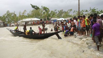 A boat brings people to land, as locals check an embankment before Cyclone Amphan made landfall, in Shyamnagar, Shatkhira, Bangladesh.