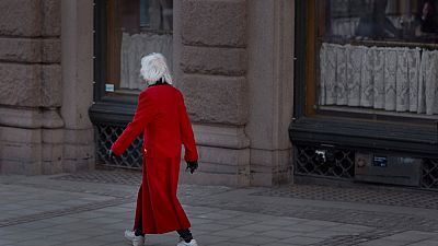 La gente beve al bar, mentre una donna anziana passa per strada a Stoccolma, Svezia