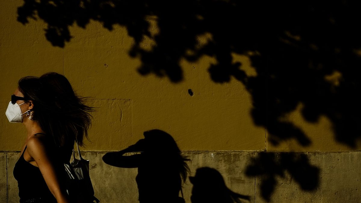 Una mujer camina con mascarilla por una calle de Pamplona