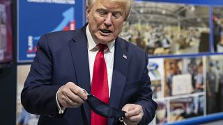 President Donald Trump holds his protective face mask