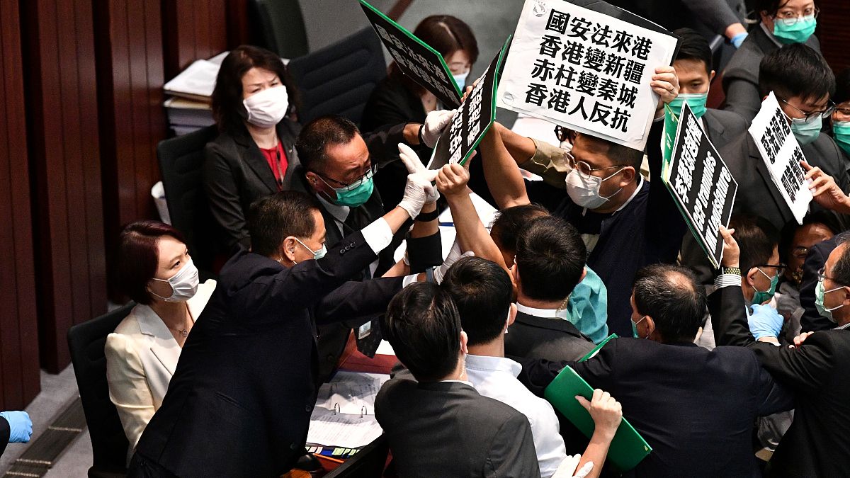 Hong Kong pro-democracy lawmakers holding up placards are blocked by security as they protest during a meeting chaired by pro-Beijing lawmakers on May 22, 2020