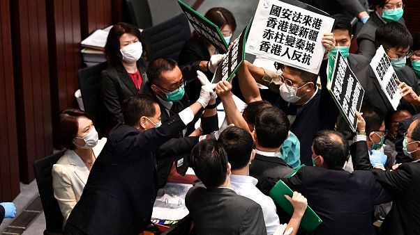 Hong Kong pro-democracy lawmakers holding up placards are blocked by security as they protest during a meeting chaired by pro-Beijing lawmakers on May 22, 2020 Hong Kong pro-democracy lawmakers holding up placards are blocked by security as they protest during a meeting chaired by pro-Beijing lawmakers on May 22, 2020