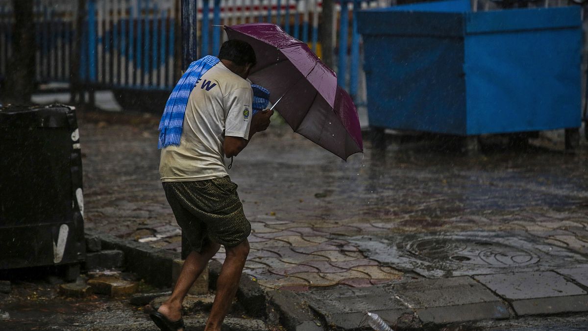 A man struggles to hold his umbrella and walk against high wind in Kolkata, India, Wednesday, May 20, 2020.