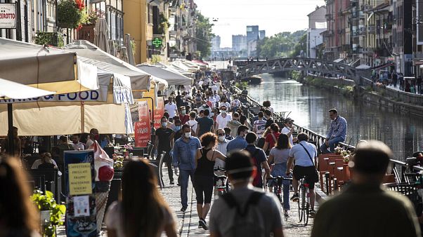 People take a walk and relax at the Naviglio Grande canal, in Milan, Italy