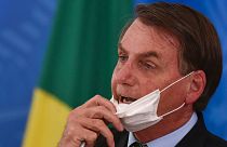 Brazil's President Jair Bolsonaro removes his mask to speak at a press conference on the new coronavirus in Brasilia, Brazil, March 18, 2020