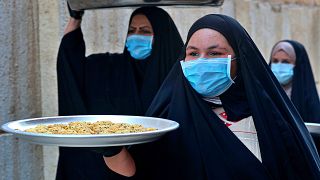 Iraqi women carry cookies for the upcoming Muslim Eid al-Fitr celebrations that mark the end of th