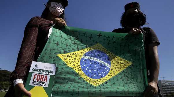 Demonstrators hold a national flag marked with black crosses during a protest demanding President Jair Bolsonaro be impeached Demonstrators hold a national flag marked with black crosses during a protest demanding President Jair Bolsonaro be impeached
