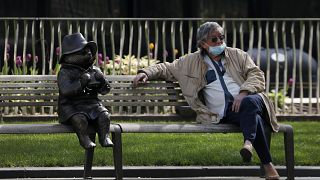 A man relaxes on a bench in London, next to a sculpture of Paddington Bear, as the country is in lockdown to help curb the spread of the coronavirus, Wednesday, April 15, 2020